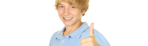 A young boy with brown hair in a blue shirt in front of a white background.