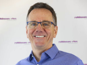 Dr. Robinson smiling in a dark blue shirt with glasses.